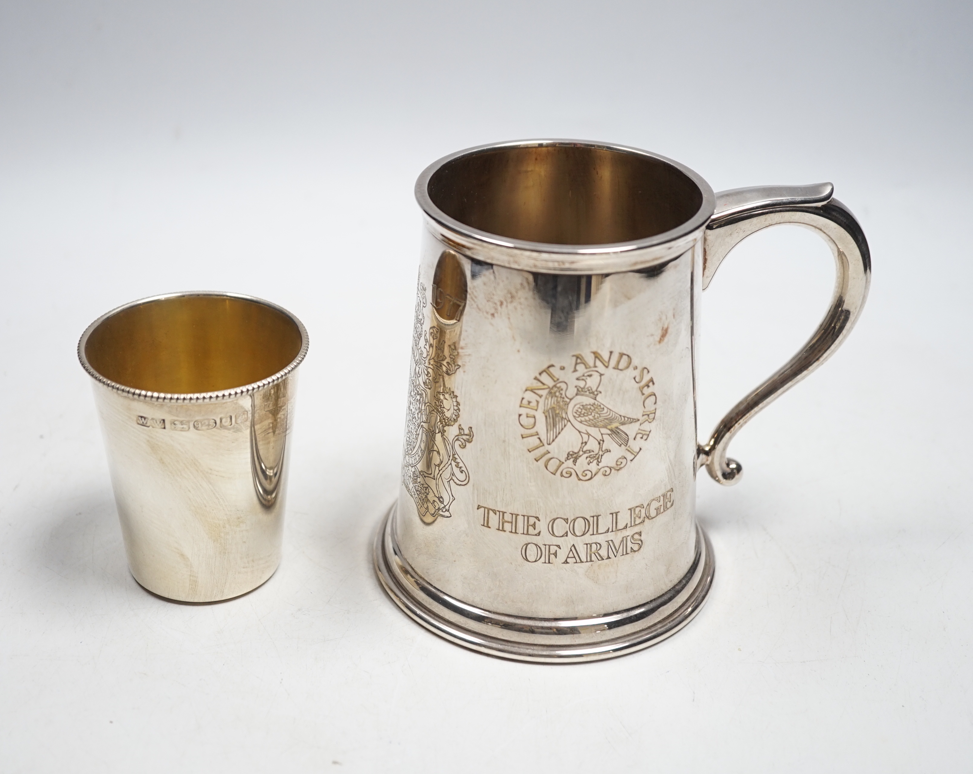 A modern silver QE11 Silver Jubilee Collage of Arms commemorative mug, 12cm, together with a modern silver beaker by WW, 13.5oz.